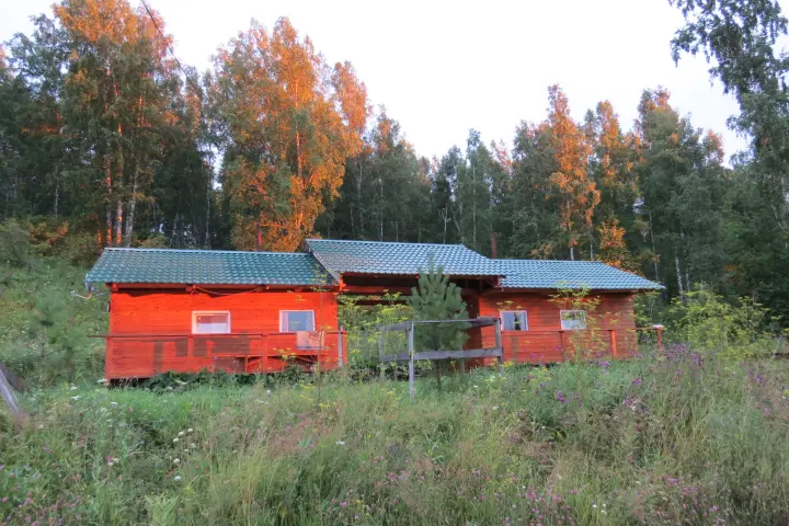 Красные деревянные домики среди осенних деревьев