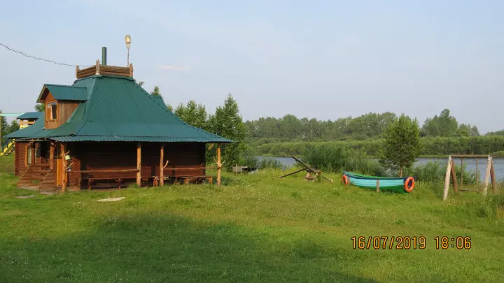 Деревянный дом на берегу и лодка у воды